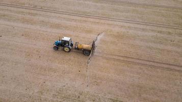vista aérea do trator agrícola arando e pulverizando no campo foto