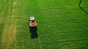 trator faz fertilizante no campo. levantamento aéreo foto