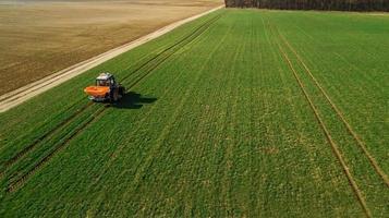 trator faz fertilizante no campo. levantamento aéreo foto