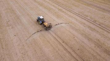 vista aérea do trator agrícola arando e pulverizando no campo foto