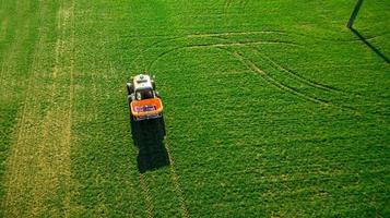 trator faz fertilizante no campo. levantamento aéreo foto