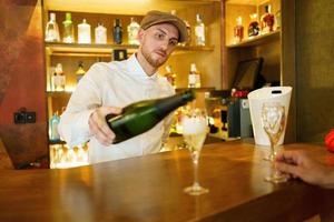 barman derramando bebida em copos no bar foto