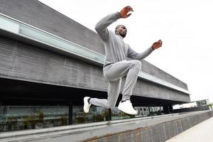 homem negro atraente correndo em meio urbano foto