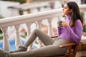 mulher persa na varanda dela tomando uma caneca de café