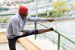 homem negro fazendo alongamento antes de correr em meio urbano foto