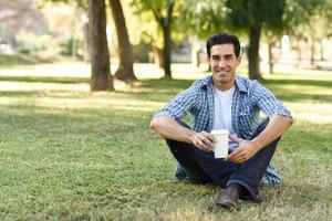 homem tomando café para ir em um parque urbano foto