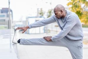 homem negro fazendo alongamento antes de correr em meio urbano foto