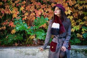 linda garota com cabelo muito comprido, vestindo casaco de inverno e boné em fundo de folhas de outono. foto