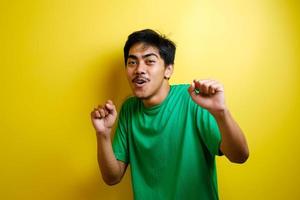 homem asiático em camiseta verde sorrindo e dançando alegremente foto