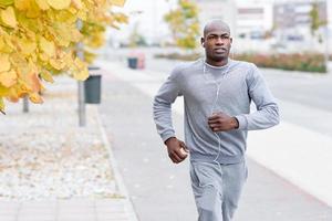 homem negro atraente correndo em meio urbano foto