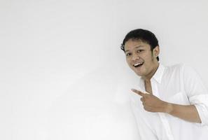 sorriso de jovem asiático de camisa branca com ponto de mão no espaço vazio foto