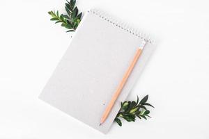 caderno de papel orgânico com galho verde sobre fundo branco. conceito de desperdício zero foto