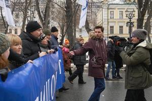 moscou, rússia - 24 de fevereiro de 2019 marcha memorial nemtsov. repórter do canal de chuva da tv russa aleksei korostelev entrevistando manifestantes carregando uma bandeira política foto