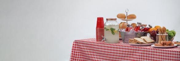 mesa de piquenique e toalha xadrez vermelha com comida e bebida para festa ao ar livre. isolado foto