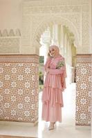 retrato de corpo inteiro de senhora usa um vestido de noiva, maquiagem de casamento no hijab. vestido de noiva malaio ou indonésia, beleza ou conceito eidul fitri. bela mulher muçulmana do sudeste asiático posando na mesquita foto
