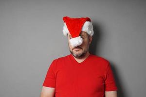 odiador de natal escondendo o rosto atrás do chapéu de papai noel foto