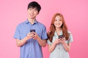 jovem casal asiático usando smartphone em fundo rosa foto