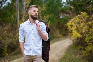 retrato de um jovem barbudo andando na estrada no parque no outono. foto