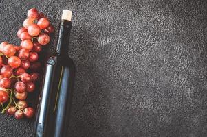 garrafa de vinho com cacho de uvas foto