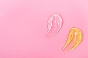 esfregaços cosméticos de gel para cuidados com a pele em um fundo rosa, creme, peeling, leite, loção, textura de gotas. closeup com espaço de cópia. foto