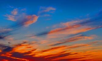 céu do sol laranja claro com algumas nuvens de superfície de fluxo abstrato nuvens de trovão no céu no pôr do sol. foto