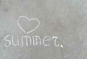 palavra de verão e coração - desenho à mão de giz branco no asfalto preto foto
