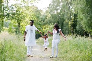 família afro-americana no vestido nacional nigeriano branco se divertindo ao ar livre foto