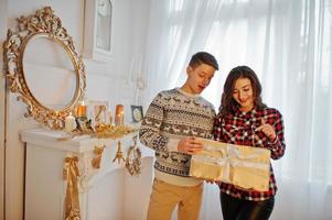 jovem casal elegante com presentes de natal e decoração de ano novo. tom de cor quente suave. foto