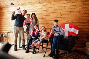 família com bandeiras da Dinamarca dentro de casa de madeira. viajar para países escandinavos. o povo dinamarquês mais feliz. foto