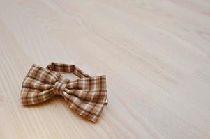 gravata borboleta xadrez marrom sobre fundo claro de madeira foto