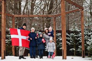 família com bandeiras da Dinamarca ao ar livre no inverno. viajar para países escandinavos. o povo dinamarquês mais feliz. foto