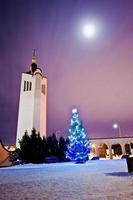 sino da igreja com árvore de ano novo com guirlanda brilhante à luz da lua na noite congelada foto