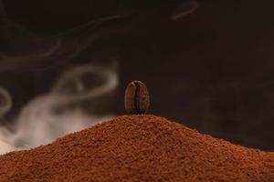 grão de café torrado fresco fica em uma dispersão de café moído na fumaça. foto