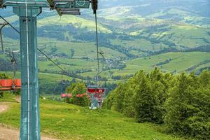 elevadores de esqui vazios sobre bela colina coberta de grama verde com floresta foto