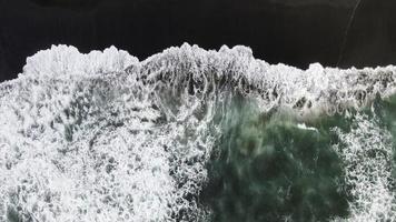 vista aérea para ondas na praia espirrando ondas com areia escura. água do mar ondulada limpa azul turquesa. foto