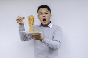 retrato de choque e uau jovem asiático gosta de macarrão. comendo o conceito de almoço. foto