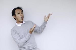 jovem asiático waer camisa branca está surpreso e gritando uau com apontando para a direita com o dedo isolado no fundo cinza com espaço de cópia para o seu texto. foto