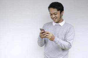 inteligente jovem asiático está feliz e sorrindo ao usar smartphone em fundo de estúdio foto