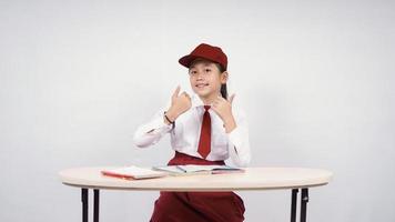 menina asiática do ensino fundamental estudando corretamente isolado no fundo branco foto