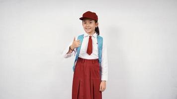 menina asiática da escola primária pronta para ir isolada no fundo branco foto