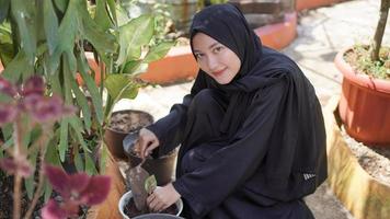 a beleza em hijab que gosta de plantar flores no jardim foto