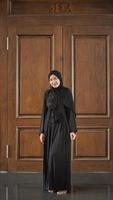 mulher de vestido preto muçulmano sorrindo fica linda na mesquita foto
