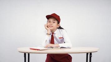 menina asiática do ensino fundamental estudando desfrutar isolado no fundo branco foto