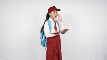 menina asiática da escola primária gritando animadamente isolada no fundo branco foto
