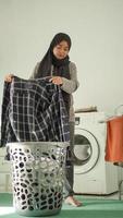 mulher asiática em hijab secando sua roupa em casa foto