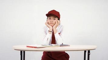 menina da escola primária asiática estudando até cansado isolado no fundo branco foto