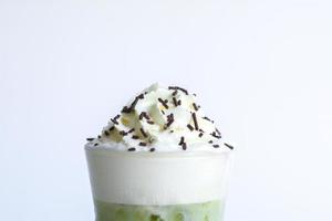 chantilly com cobertura de açúcar de chocolate no gelo matcha e chá verde sobre fundo branco. lanche doce e delicioso no conceito de festa. foto