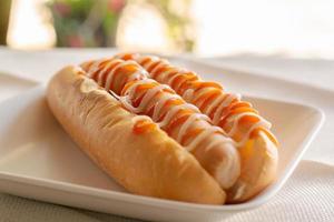 cachorro-quente com pão e ketchup, maionese na chapa branca. sanduíche de salsicha para o almoço. conceito de fast-food. foto