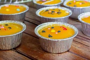 feche o bolo de laranja mínimo com creme de manteiga em copo de papel alumínio na mesa de madeira. deliciosa padaria em tempos de café e chá foto