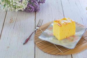 pedaço de bolo de coco chiffon de baunilha no prato quadrado na mesa de madeira. deliciosa pequena padaria para café e chá. foto